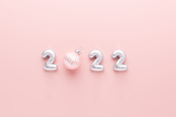 New year composition with silver numbers 2022 and christmas ball on pink background. New year celebration