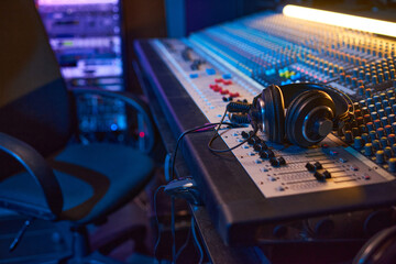 Obraz na płótnie Canvas Close-up of sound mixing board with headphones on it for musical producer in studio