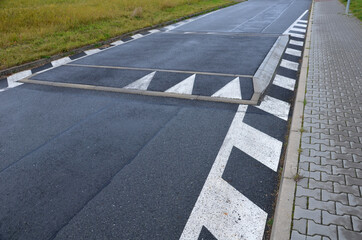 Fototapeta premium a regular square raised above the level of the asphalt road beveled on all sides. overcoming an obstacle means slowing down the vehicle and thus increasing safety in the residential area near school