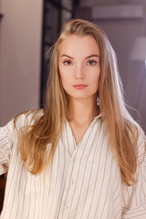 Fototapeta premium Blonde girl in casual clothes looking at camera at home