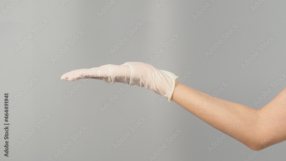 Wall mural empty hand wearing white latex glove or medical glove on grey background.