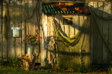 Romantic fishing village landscape. Old wooden building with fishing net and flowers
