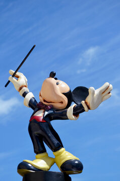  Studio image of Mickey Mouse figure Standing on a wall with a blue sky background.  