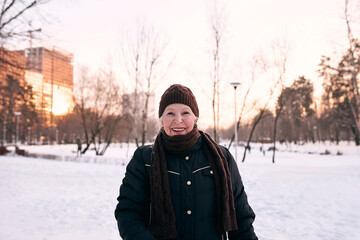 Fototapeta na wymiar senior woman in hat and sporty jacket jogging in snow winter park. Winter, age, sport, activity, season concept