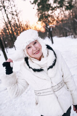 senior woman in white hat and fur coat enjoying winter in snow forest. Winter, age, season concept