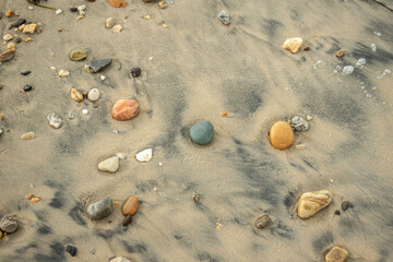 Constellation of colored pebbles on the sandy shore