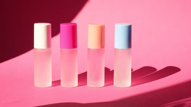shade from a swaying palm leaf on several spray glass bottles with perfume on pink geometric podiums, composition for perfume presentation, four perfume bottles on stage, pink background