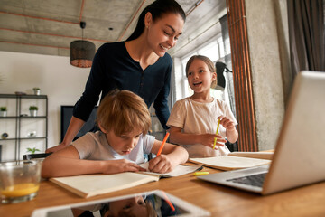 Fototapeta na wymiar Smiling mother and teen kids do homework on computer