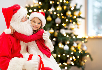 winter holidays, celebration and people concept - smiling girl hugging santa claus at home over christmas tree lights on background