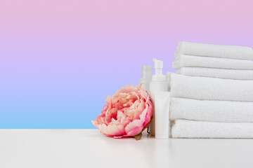 Stacked clean towels on white table against color background