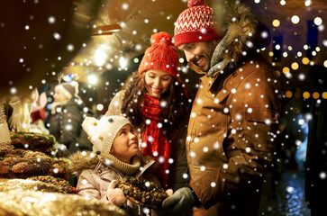 family, winter holidays and celebration concept - happy mother, father and little daughter buying...