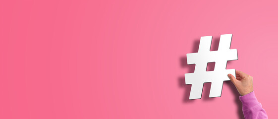 hand holding hash symbol, hashtag against pink background, social media concept with copy space