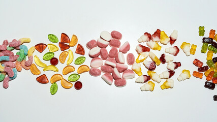Pile of multicolored tasty gummy candies in different shapes isolated over white background