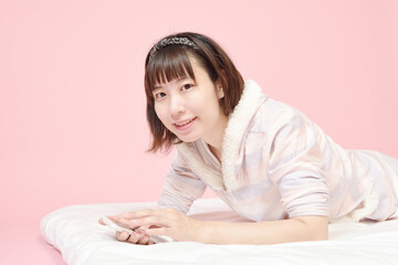 Naklejka premium 寝転んでスマホを見る若い女性