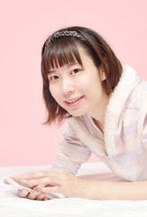 Naklejka premium 寝転んでスマホを見る若い女性