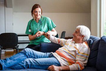 Smiling female doctor of the medical health system putting a smartwatch on a old man, nurse helping senior man with modern smart watch and showing functions, smartwatch for assisted living concept