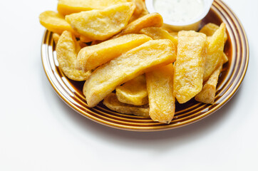 Deep fried and crispy delicious fries on the ceramic plate with garlic dip