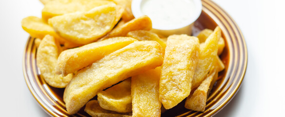 Deep fried and crispy delicious fries on the ceramic plate with garlic dip
