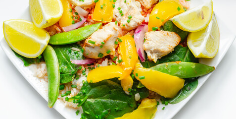 Cooked chicken breast pieces with peppers, sugar snap peas, and baby leaf spinach in a spicy sweet and sour sauce with fragrant rice