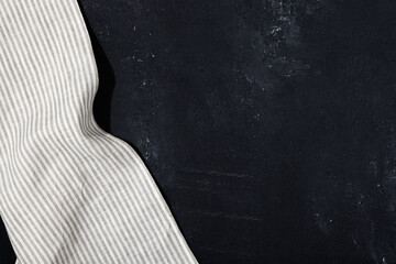Striped textile gray serving napkin on black plastered background