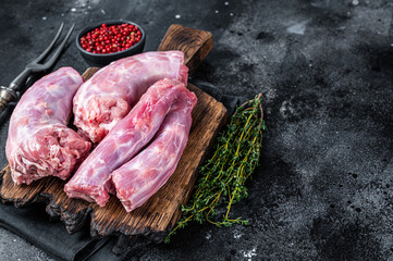 Raw Turkey neck meat on a butcher wooden board. Black background. Top View. Copy space