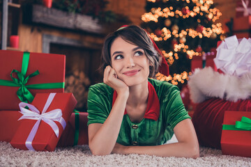 Portrait of attractive cheery dreamy girl elf lying on carpet thinking december day at home modern...