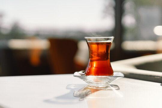 Turkish tea served in tulip-shaped glass on rustic table. Turkish tea in traditional glass cup. Turkish traditional hot drink