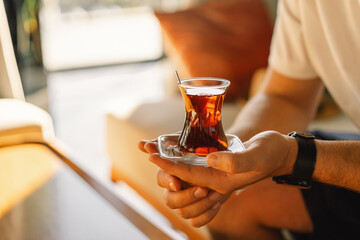 A man drinks Turkish traditional hot tea in the lobby of a Turkish hotel. Turkish tea and...