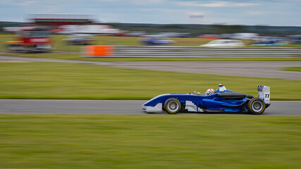 A panning shot of a racing car as it circuits a track.