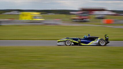A panning shot of a racing car as it circuits a track.
