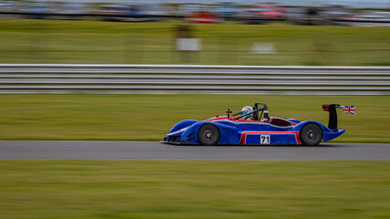 A panning shot of a racing car as it circuits a track.