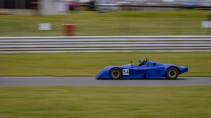A panning shot of a racing car as it circuits a track.