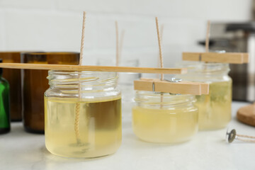 Glass jars with melted wax on white table. Handmade candles