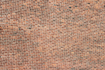 A wide brick blank wall of an old building. Uneven brickwork on a large wall.