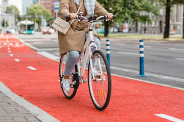 Fototapeta na wymiar traffic, city transport and people concept - woman riding bicycle along red bike lane or two way road on street