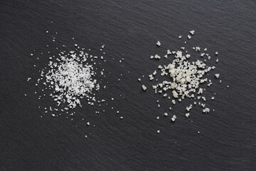 Fototapeta na wymiar Two different types of traditional salt of high quality: the salt flower on the left and the coarse sel on the right on a black background. 