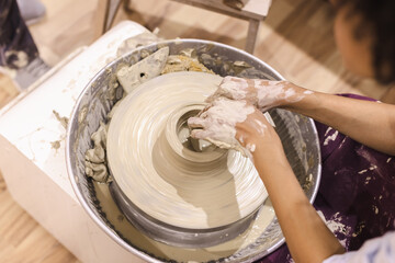Pottery workshop. Female ceramic artist molding clay on pottery wheel. Creative handmade craft.