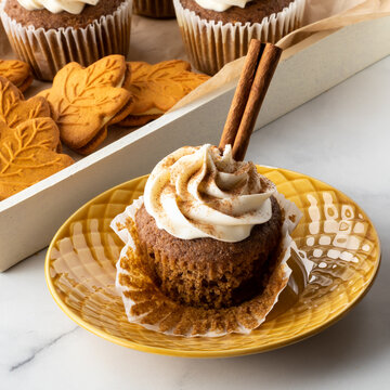 Close up of a pumpkin spice cupcake topped with cream cheese frosting.