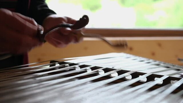 Close up of dulcimer string and wooden bat. Playing traditional musical instruments. Closeup hand play hammered dulcimer