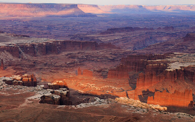 Desert canyon landscape at sunset, with dramatic rock towers and maze of cliffs extending into the distance. Canyonlands, Utah.