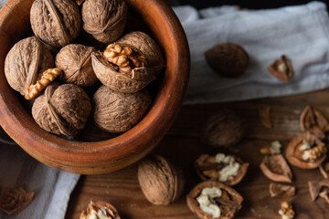 Closed and open walnuts inside a bowl on a table
