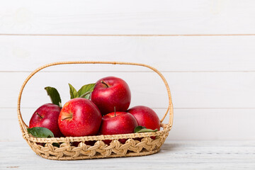 Ripe garden apple fruits with leaves in basket on wooden table. Top view flat lay with copy space