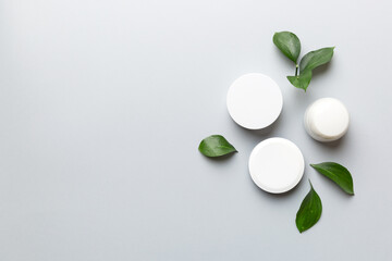 Organic cosmetic products with green leaves on color background. Copy space, flat lay
