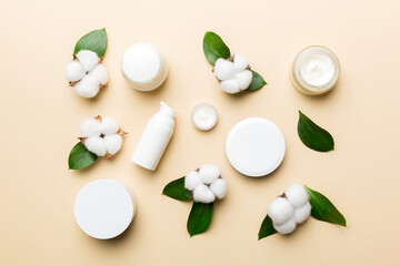 Organic cosmetic products with cotton flower and green leaves on color background. Flat lay