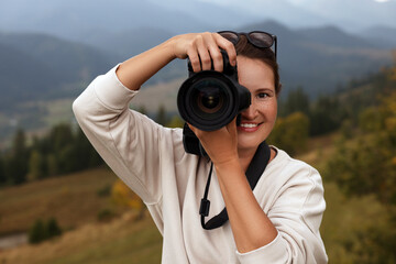 Professional photographer taking picture with modern camera in mountains