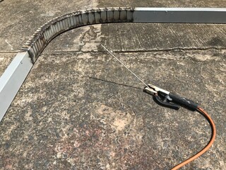 Steel was bent to be a curve. It is set on a concrete floor beside the welding equipment.