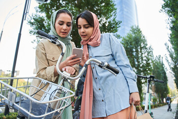 Millennial muslim woman in abayas using smartphone to unlocking urban bike