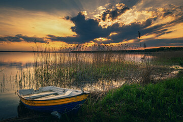 sunset on the lake and boat in wytyckie lake, poland lubelskie