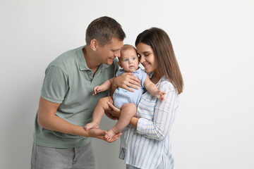 Fototapeta premium Portrait of happy family with their cute baby on white background