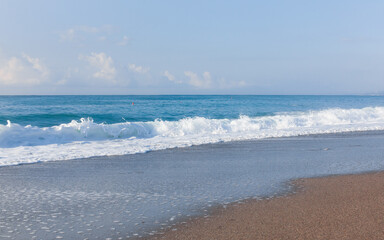 Fototapeta na wymiar Waves on the beach. Sand and blue water. Sicily, Italy.